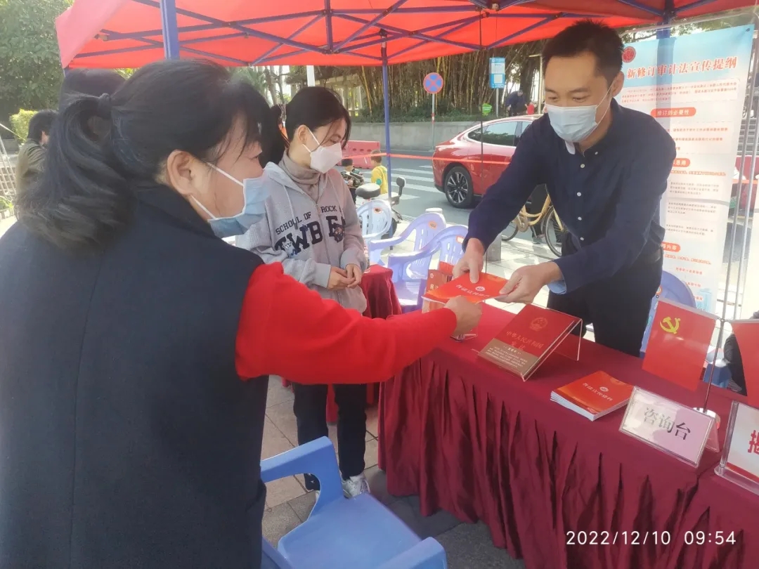 图为周航（右一）在审计普法宣传现场，向群众宣传审计法规、发放宣传材料